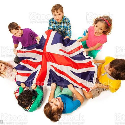 Top view of seven kids holding English flag in the middle of their circle, isolated on white background